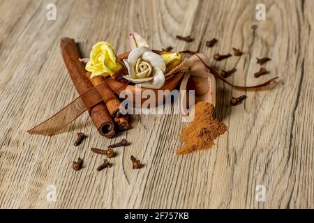 Composition with ground and stick cinnamon, cloves and decorative flowers on wooden table Stock Photo