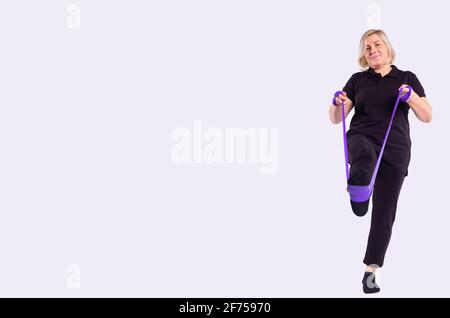 Senior woman in a studio doing exercises with an elastic band on a white background Stock Photo