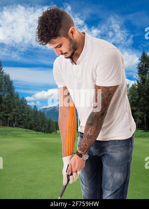 Man playing golf in green field with adhesive tape on arm Stock Photo