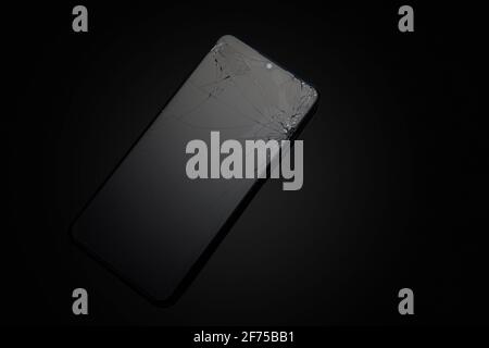 Modern touchscreen smartphone with broken screen on dark background Stock Photo