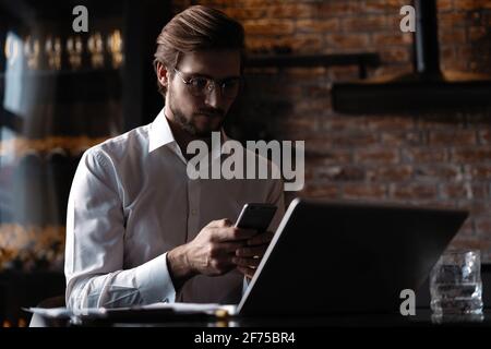 Casual man relaxed using smart phone, young man browsing on smart phone in cafe interior. Stock Photo