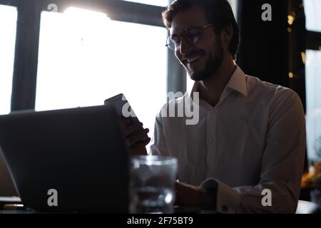 Casual man relaxed using smart phone, young man browsing on smart phone in cafe interior. Stock Photo