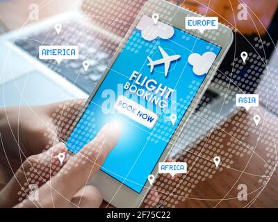Flight booking online with smartphone. Finger touching on mobile phone for booking air flight online airline ticket near laptop computer on wooden tab Stock Photo