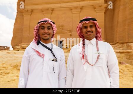 AlUla, Saudi Arabia, February 19 2020: Two young Saudi Arabian tour guides pose in front of the tomb of Lihyan son of Kuza, known as Qasr AlFarid, the Stock Photo