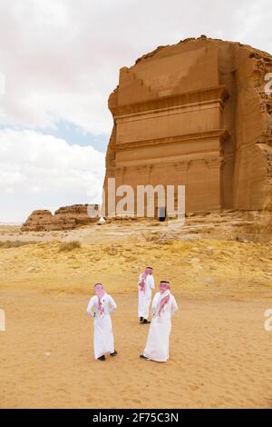 AlUla, Saudi Arabia, February 19 2020: Three Saudis stand in front of the tomb of Lihyan son of Kuza, known as Qasr AlFarid, the most iconic tomb in A Stock Photo