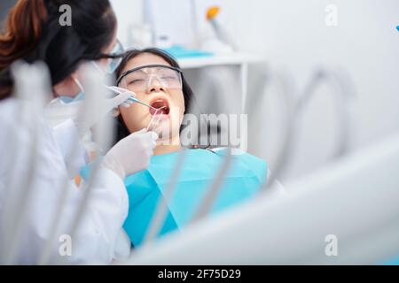 Pretty young Asian woman getting her teeth treated in dental clinic Stock Photo