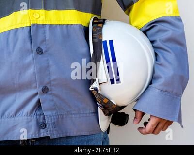 Engineering people wearing yellow high visibility safety jacket holding white safety helmet or hard hat isolated on white background. Stock Photo