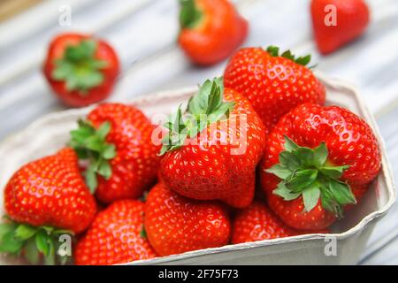 Closeup of isolated ripe fresh strawberries from german farmers market in cardboard box on white wood table Stock Photo