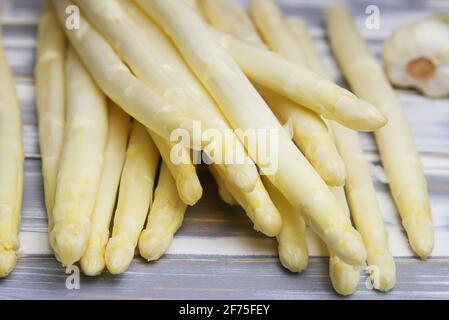 Closeup of isolated pile raw white uncooked asparagus spears on wood table Stock Photo