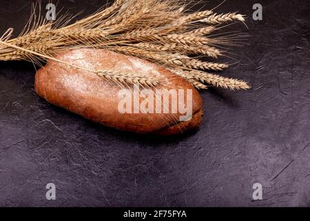 Brown buckwheat loaf on black surface. Freshly baked homemade bread. Stock Photo