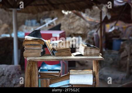 Old yellowed books lie on a heap on the counter of a flea market outdoors on a blurred background. Stock Photo