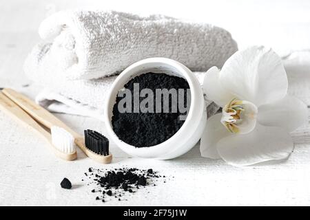 Composition with a wooden natural toothbrushes, black teeth whitening powder and orchid flower copy space. Stock Photo