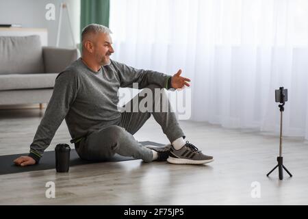 Handsome senior man fitness coach broadcasting from home Stock Photo