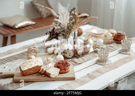 Table with Easter decor elements and festive pastries. Cozy home composition. Stock Photo