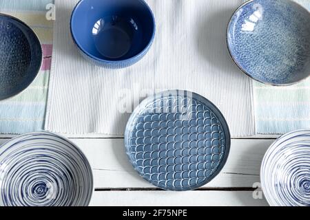 Empty ceramic tableware. Ceramic plates on wooden surface. Overview empty food table with tableware. Set of different modern blue plates. Stock Photo