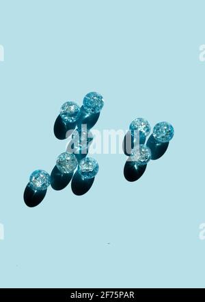 Blue glass beads on a blue background. Hard shadow and reflection. DIY handmade gift. Stock Photo