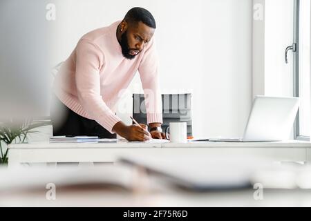 Confident attractive young african businessman working in the office, using laptop computer Stock Photo