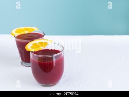 Beet juice on white and blue background with orange slices decoration. Copy space. Stock Photo
