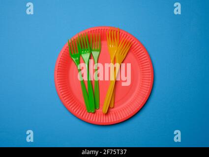 green, orange plastic forks and empty red paper disposable plates on a blue background, set Stock Photo