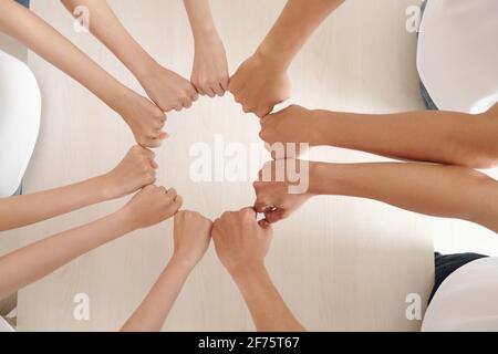Hands of volunteers of charity center making circle with clenched fists, expressing support and unity Stock Photo