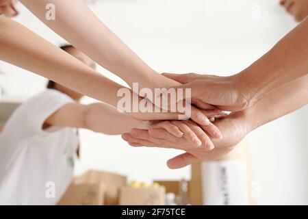 Volunteers stacking hands to support each other before starting work on big project Stock Photo