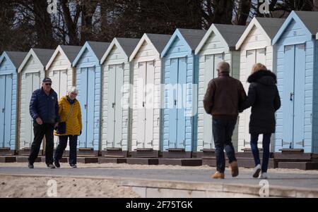 People make their way past beach huts on Avon beach in Mudeford, Dorset. Picture date: Monday April 5, 2021.
