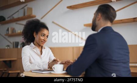 positive african american businesswoman talking with blurred partner during meeting in cafe Stock Photo