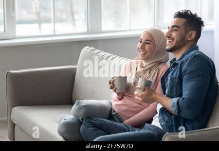 Joyful arab couple drinking coffee and looking at copy space Stock Photo
