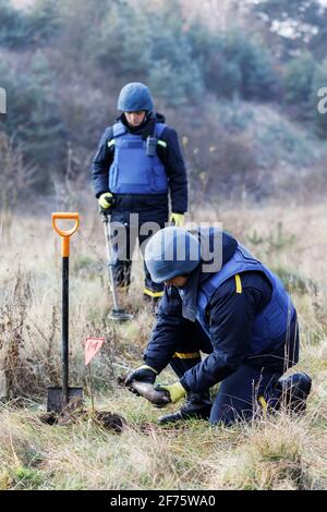 A man in a special suit works with a detector and found an explosive device. Stock Photo