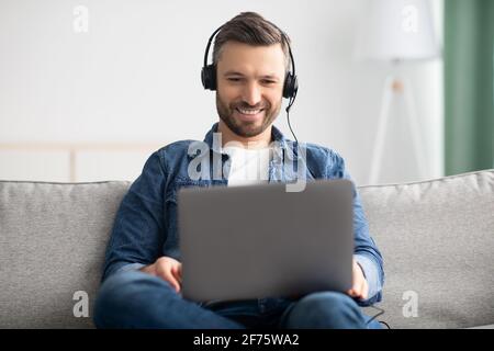 Relaxed man watching movie, using laptop and headphones Stock Photo