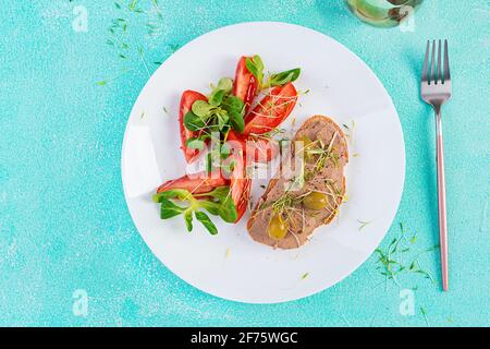Fresh homemade chicken liver pate on bread and tomatoes salad. Breakfast. Top view, flat lay, above Stock Photo