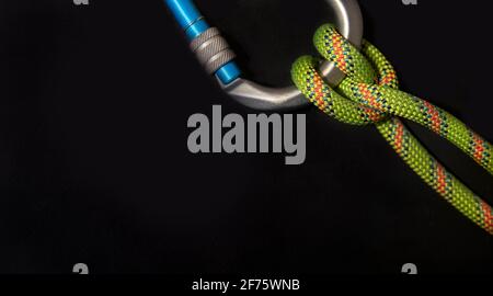 Diagonal carabiner with boatman's knot and fluorescent green rope on a black background Stock Photo