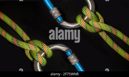 Inverse carabiners with boatman's knot and fluorescent green rope on a black background Stock Photo