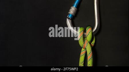 Vertical Carabiner with boatman's knot and fluorescent green rope on a black background Stock Photo