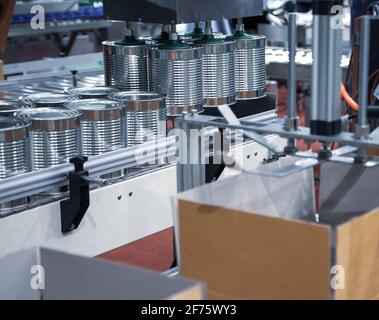 Automation robot lifting food can into cardboard in production line. Food industry. Stock Photo