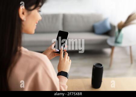 Back view of woman using phone with empty mockup screen Stock Photo