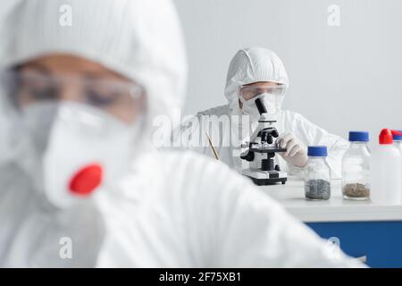 Scientist using microscope while working near colleague on blurred foreground Stock Photo