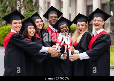 Diverse International Students With Diplomas Celebrating Graduation Stock Photo