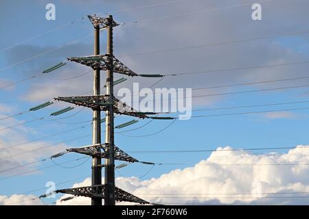High voltage tower with electrical wires on blue sky with white clouds. Electricity transmission lines, power supply concept Stock Photo