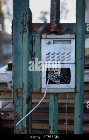 Broken entryphone in metal entrance gate, damaged and open with visible circuit board and cables Stock Photo