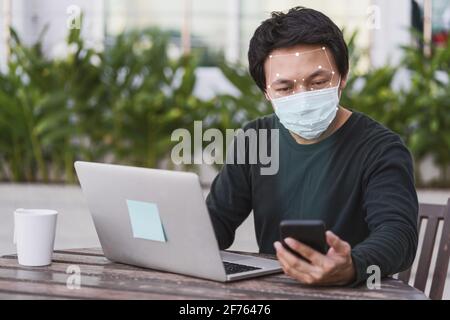 Asian business man in casual clothes using mobile phone for biometric scan and face detection when working at home,Technology and new normal Covid-19 Stock Photo