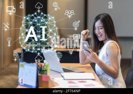 Polygonal brain shape of an artificial intelligence with AI text and various icon of smart city Internet of Things Technology over Asian businesswomen Stock Photo