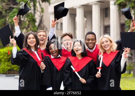 Joyful multiethnic students with diplomas celebrating graduation Stock Photo