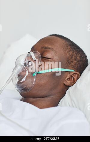 Closeup side view portrait of African-American man in hospital bed with oxygen mask Stock Photo