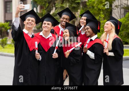 Positive multiracial group of students taking selfie on smartphone Stock Photo