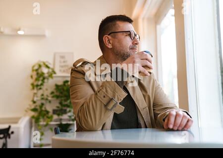Handsome confident businessman having breakfast in modern coffee shop Stock Photo