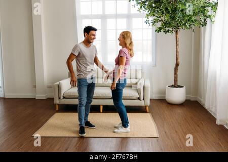 Young and handsome caucasian man and beautiful woman doing romantic couple in love holding hand and spending time together at home and feeling excited Stock Photo