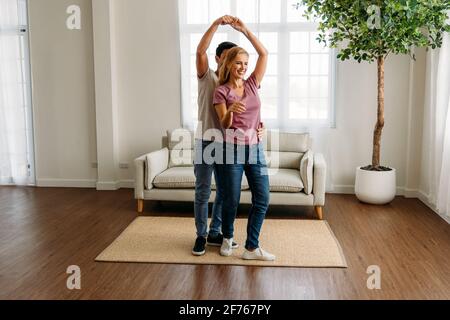 Young and handsome caucasian man and beautiful woman doing romantic couple in love dancing spending time together at home and feeling excited Stock Photo