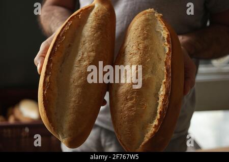 Hands of chef baker holding two loaves of fresh baked bread. Stock Photo
