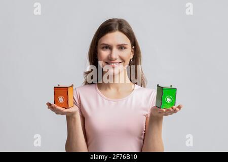 Smiling Woman Holding Small Toy Recycle Bins For Different Type Of Waste Stock Photo